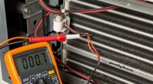 Technician testing an AC sensor with a multimeter near evaporator coil